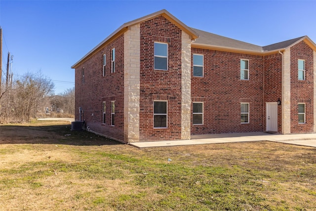 view of property exterior with brick siding, a patio, and a lawn