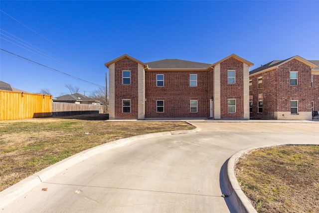 view of front facade featuring a front yard, brick siding, and fence