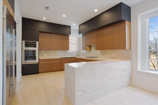 kitchen with light countertops, decorative backsplash, appliances with stainless steel finishes, a sink, and dark cabinetry