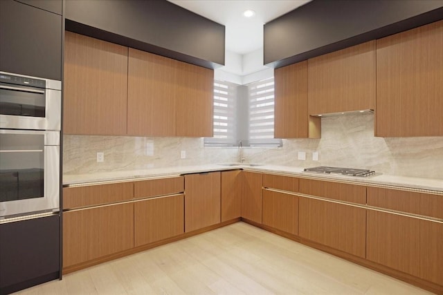 kitchen featuring decorative backsplash, appliances with stainless steel finishes, light countertops, a sink, and recessed lighting