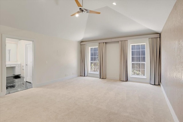 unfurnished bedroom featuring ensuite bathroom, high vaulted ceiling, light colored carpet, a ceiling fan, and baseboards