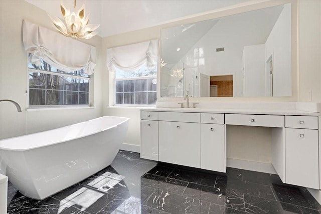 bathroom with marble finish floor, a freestanding tub, vanity, and an inviting chandelier