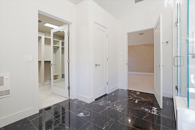 bathroom featuring visible vents, baseboards, marble finish floor, a walk in closet, and a shower stall