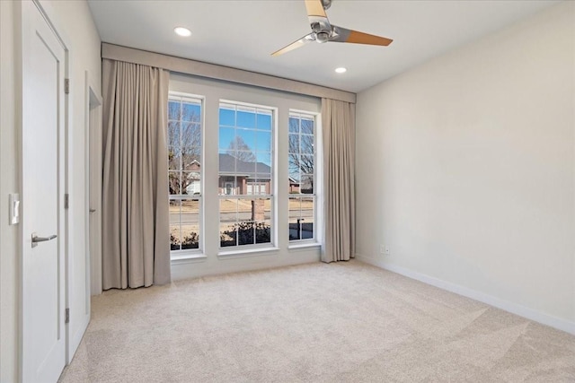 spare room featuring a ceiling fan, recessed lighting, light colored carpet, and baseboards