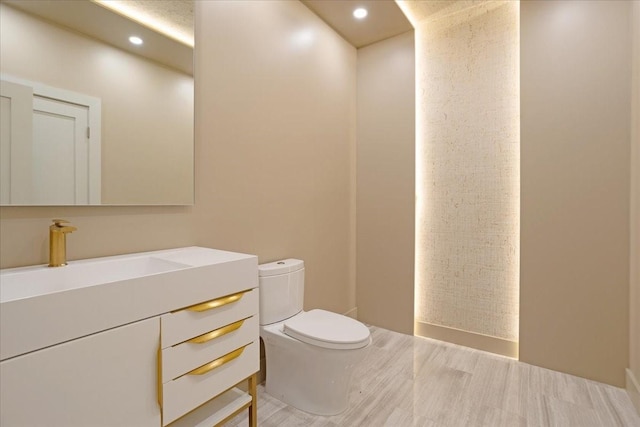 half bath featuring toilet, recessed lighting, and vanity