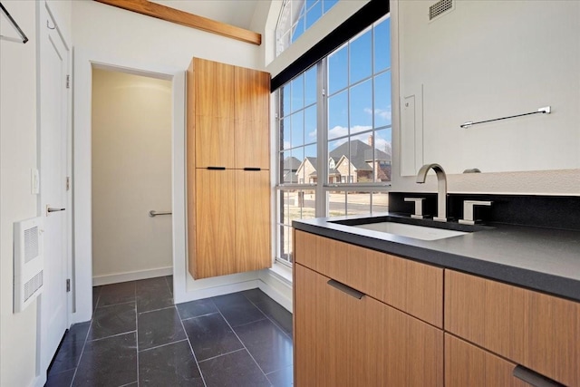 kitchen featuring dark tile patterned flooring, a sink, visible vents, dark countertops, and modern cabinets