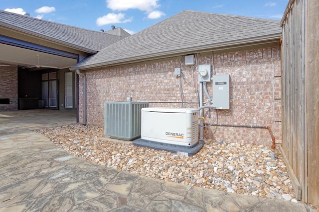 exterior details with brick siding, a shingled roof, central AC unit, electric meter, and a power unit