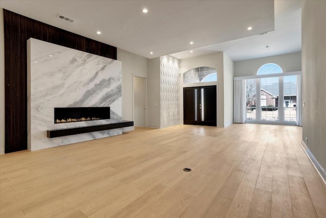 unfurnished living room featuring light wood-type flooring, visible vents, a fireplace, and recessed lighting