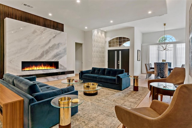 living area with visible vents, a premium fireplace, a high ceiling, a chandelier, and recessed lighting