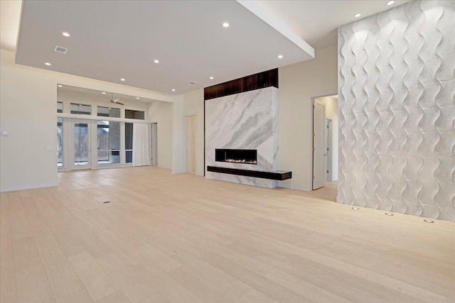 unfurnished living room featuring light wood finished floors, visible vents, french doors, a fireplace, and recessed lighting