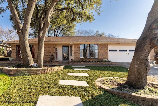 ranch-style home featuring a garage, a front yard, brick siding, and driveway