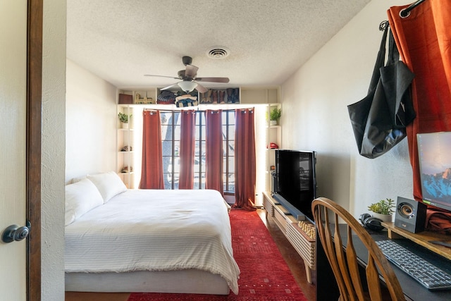 bedroom featuring a textured ceiling, ceiling fan, a textured wall, visible vents, and dark colored carpet