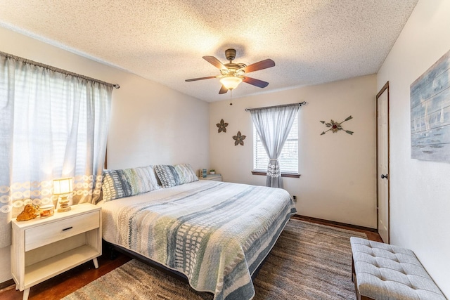 bedroom with baseboards, a ceiling fan, dark wood-style flooring, and a textured ceiling