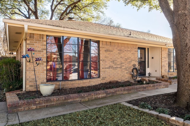 view of front of house featuring a shingled roof and brick siding