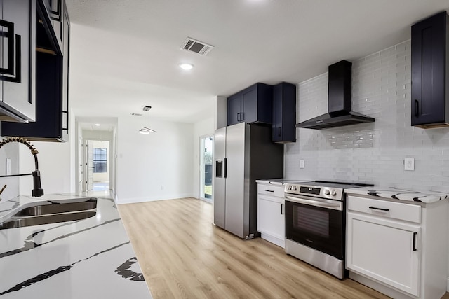 kitchen featuring light wood finished floors, light countertops, visible vents, appliances with stainless steel finishes, and wall chimney range hood