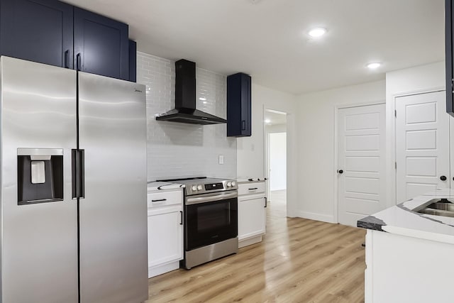 kitchen featuring stainless steel appliances, tasteful backsplash, light countertops, wall chimney range hood, and light wood-type flooring