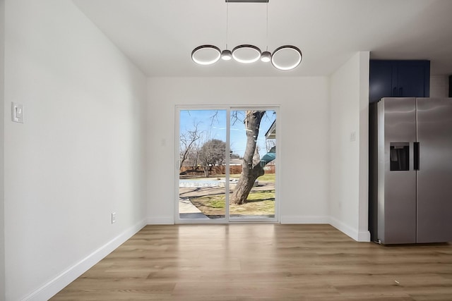 unfurnished dining area with light wood finished floors and baseboards