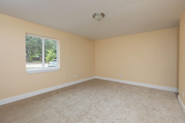 empty room featuring baseboards and light colored carpet