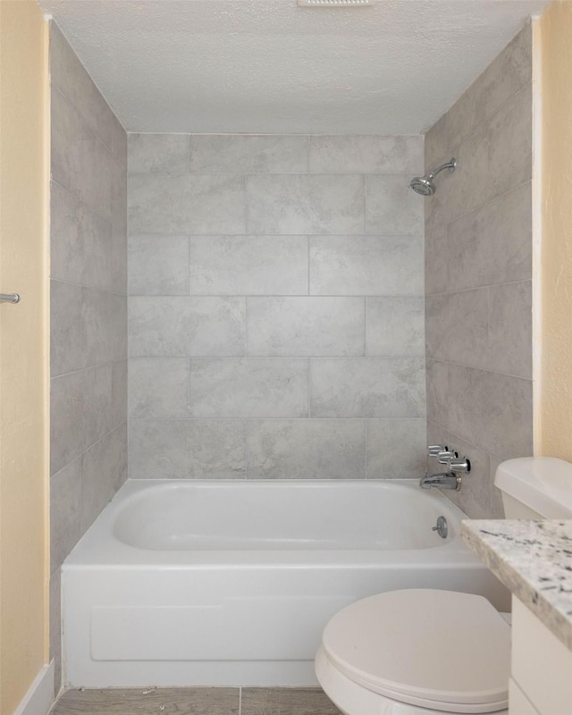 full bath featuring a textured ceiling, vanity, shower / tub combination, and toilet