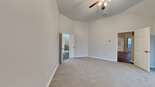 empty room featuring light colored carpet, visible vents, a high ceiling, ceiling fan, and baseboards