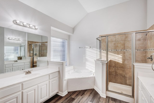 bathroom featuring two vanities, a stall shower, vaulted ceiling, a sink, and a whirlpool tub