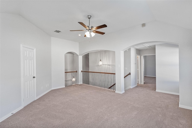 carpeted empty room with a ceiling fan, arched walkways, visible vents, and vaulted ceiling