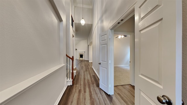 hall featuring baseboards, wood finished floors, and an upstairs landing