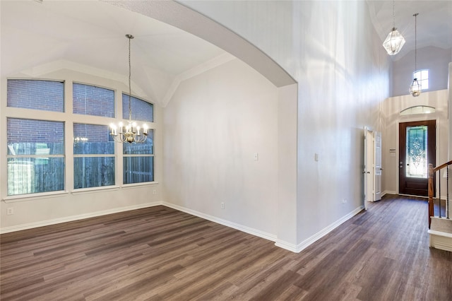 foyer entrance featuring arched walkways, dark wood-type flooring, a chandelier, and baseboards