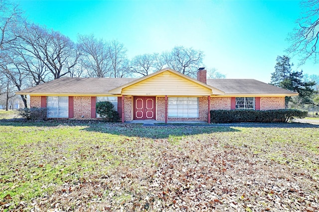 ranch-style house with a front yard, brick siding, and a chimney