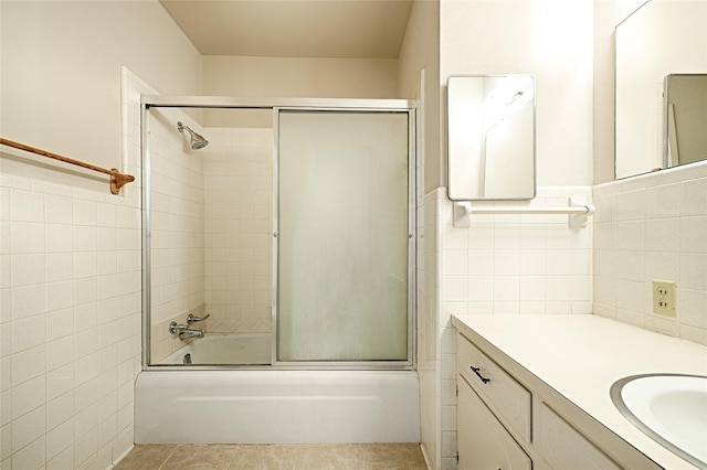 bathroom featuring bath / shower combo with glass door, vanity, tile walls, wainscoting, and tile patterned floors