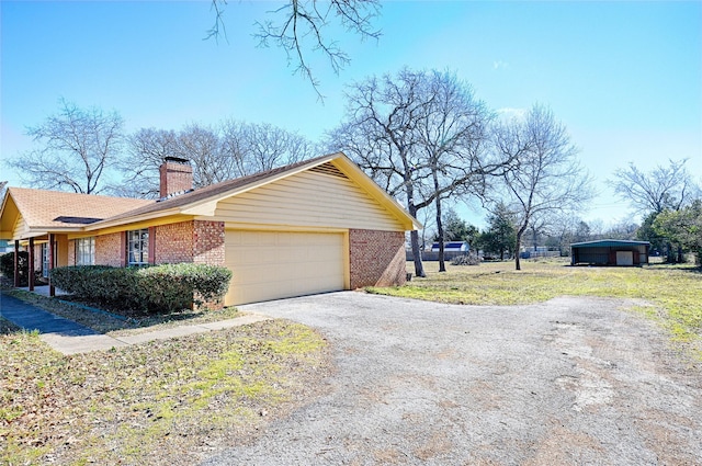 view of property exterior featuring brick siding, driveway, a chimney, and an attached garage