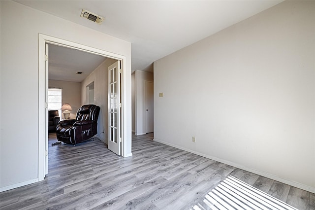 unfurnished room featuring visible vents, light wood-style flooring, and baseboards