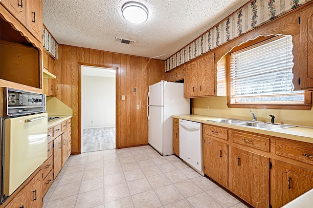 kitchen with white appliances, visible vents, brown cabinetry, light countertops, and a sink