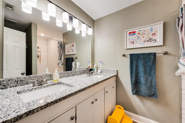 bathroom featuring double vanity, visible vents, a sink, and tiled shower