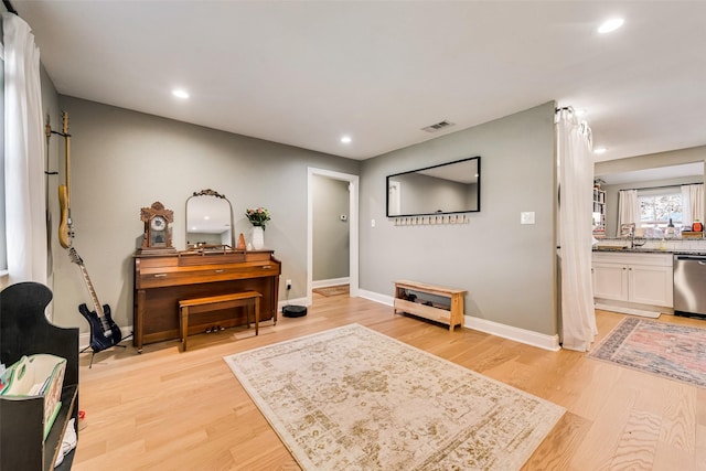 living area with light wood finished floors, recessed lighting, visible vents, and baseboards