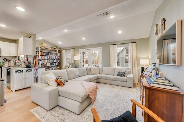 living area featuring recessed lighting, visible vents, light wood-style floors, vaulted ceiling, and french doors