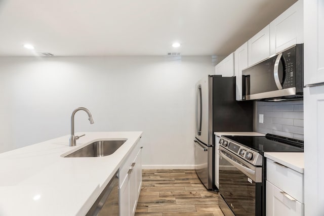 kitchen with stainless steel appliances, white cabinets, light countertops, and a sink