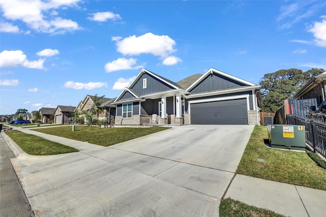 craftsman-style house featuring an attached garage, fence, driveway, board and batten siding, and a front yard