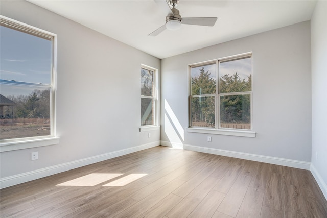 spare room with a ceiling fan, light wood-style flooring, and baseboards