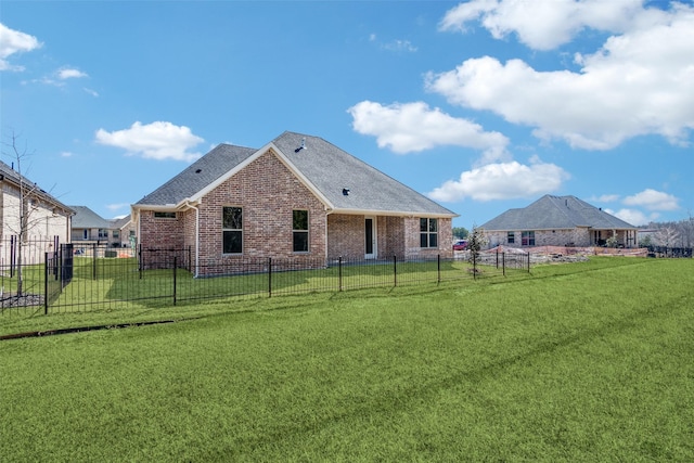 rear view of property featuring a yard, brick siding, and fence private yard