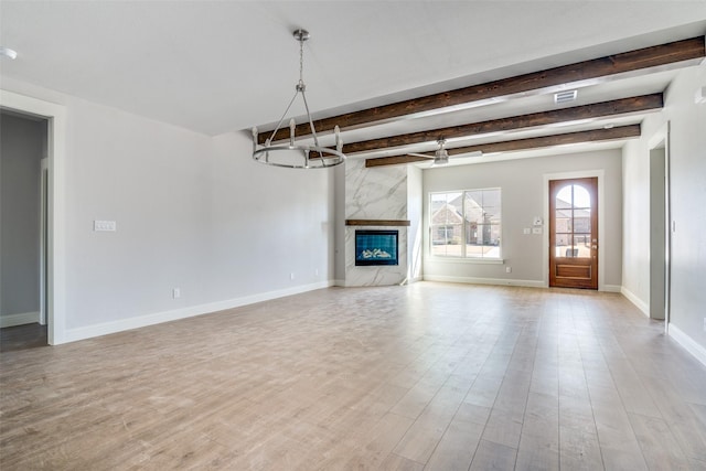 unfurnished living room with light wood-style flooring, a premium fireplace, baseboards, and ceiling fan with notable chandelier