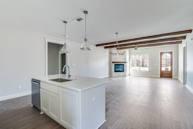 kitchen featuring decorative light fixtures, a center island with sink, visible vents, white cabinetry, and a sink