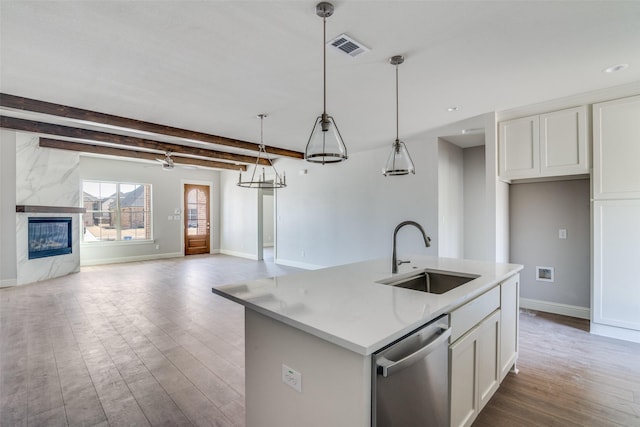 kitchen with dishwasher, white cabinetry, open floor plan, and a sink