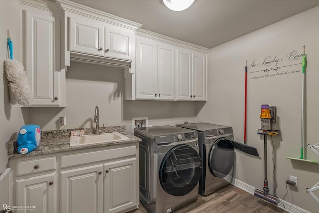 laundry area with washer and clothes dryer, cabinet space, dark wood-type flooring, a sink, and baseboards