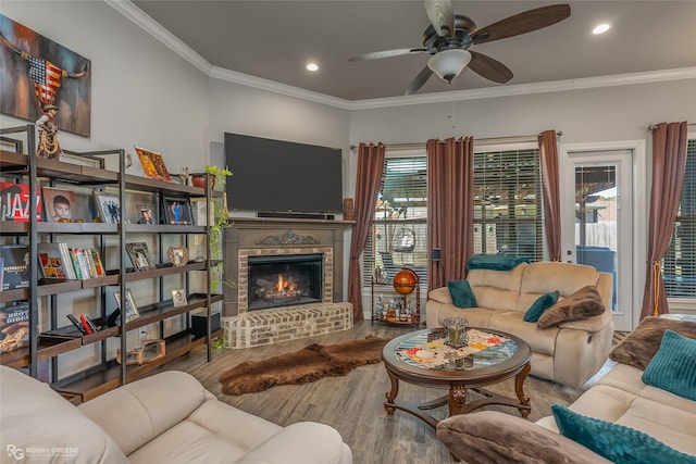 living room featuring a brick fireplace, ceiling fan, ornamental molding, and wood finished floors