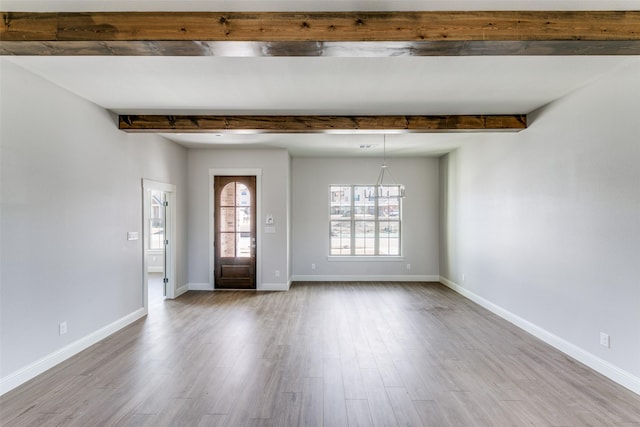 entryway featuring light wood-style floors, baseboards, and beamed ceiling