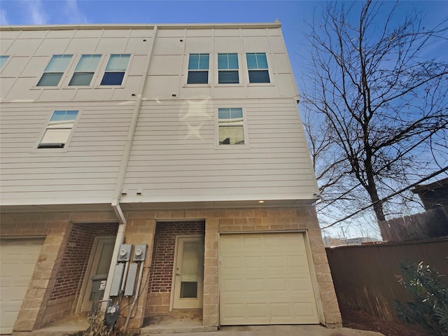 multi unit property with brick siding, fence, and an attached garage