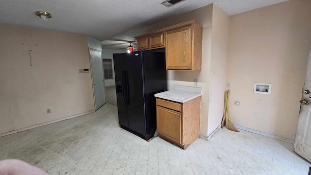 kitchen with visible vents, light countertops, brown cabinets, light floors, and black refrigerator with ice dispenser