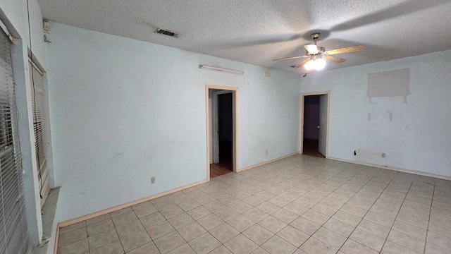 unfurnished room with visible vents, ceiling fan, a textured ceiling, and baseboards