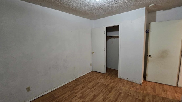 unfurnished bedroom featuring a textured ceiling, light wood finished floors, and a closet